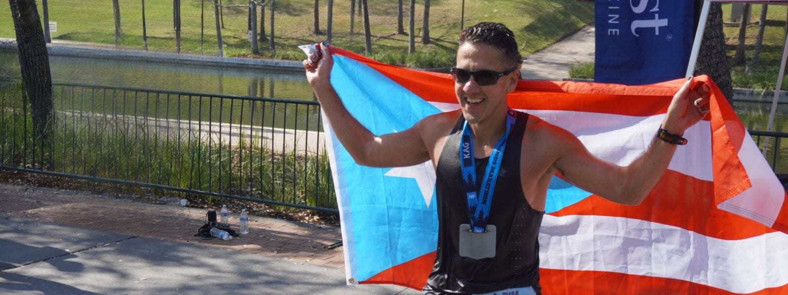 Online road running coaching athlete holding a flag at the finish of The Woodlands Marathon